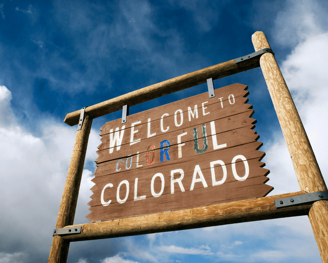 Welcome to colorful Colorado billboard made of wood with sky in the background