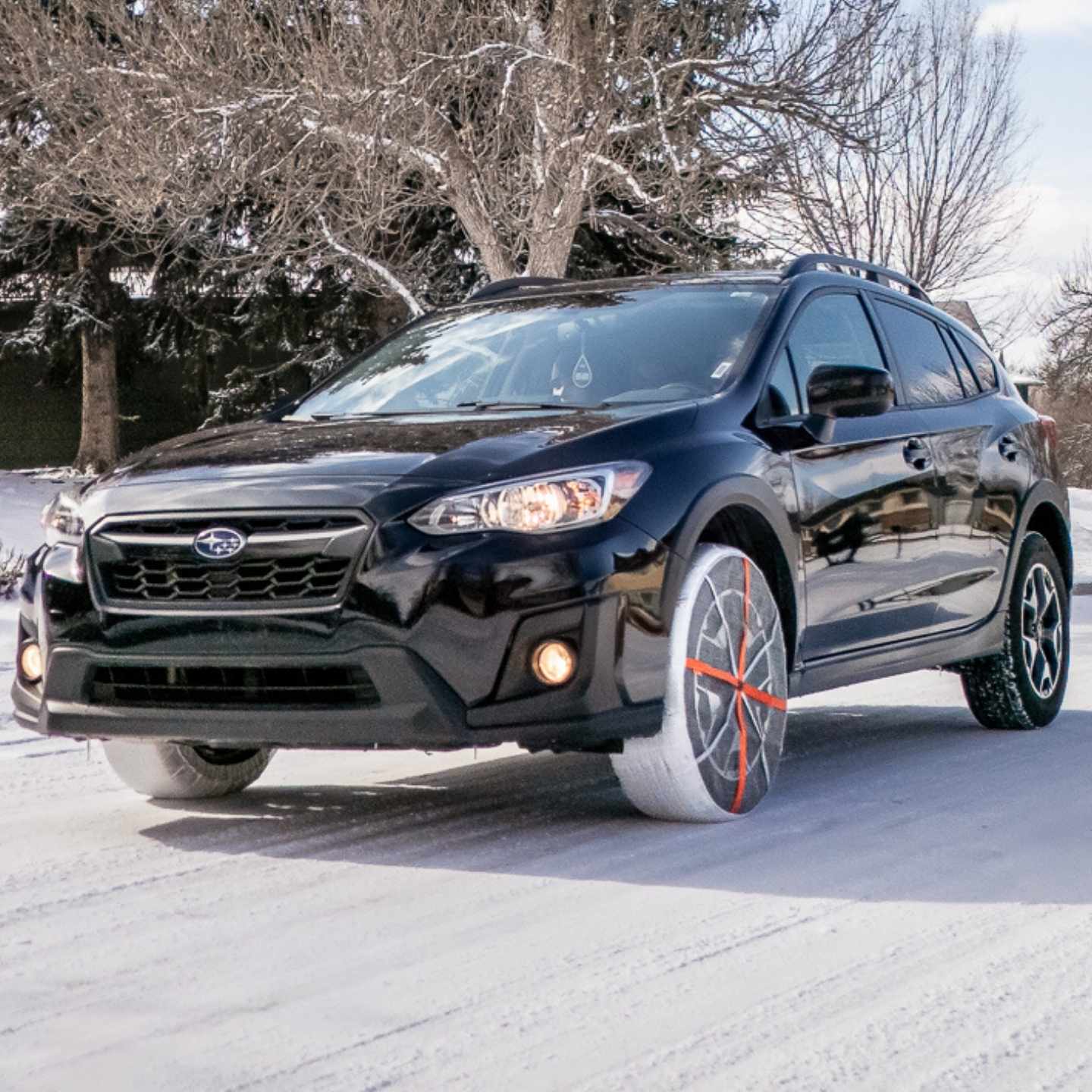 Textile snow chains installed on Subaru passenger car driving on snow